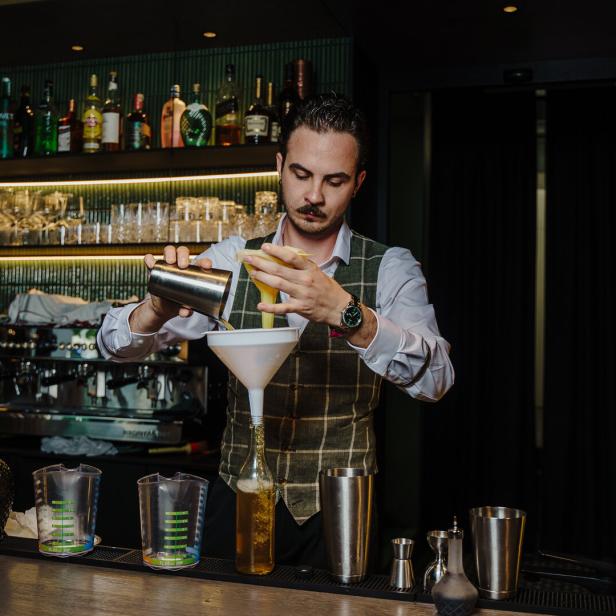 Ein Barkeeper mixt einen Cocktail hinter der Bar.