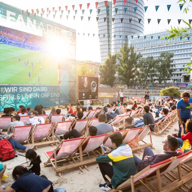 Zuschauer verfolgen ein Fußballspiel auf einer Leinwand in der Strandbar Herrmann.