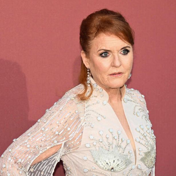Sarah Ferguson posiert vor einem roten Hintergrund.