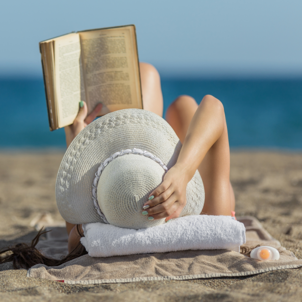 Frau liest am Strand ein Buch.