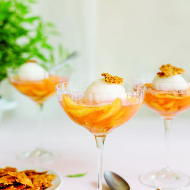 Drei Dessertgläser gefüllt mit Pfirsichspalten, einer Kugel Eis und Krokant.