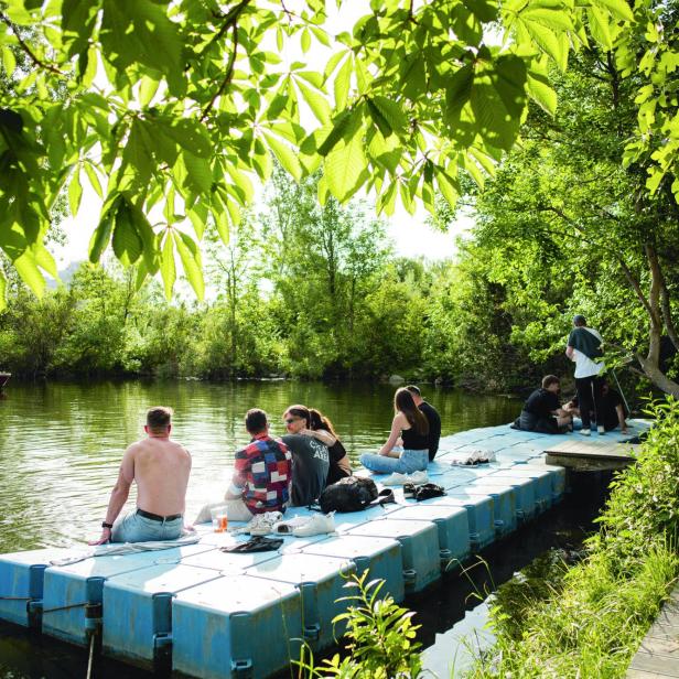 Eine Gruppe von Menschen entspannt sich auf einem Ponton am Ufer eines Sees.