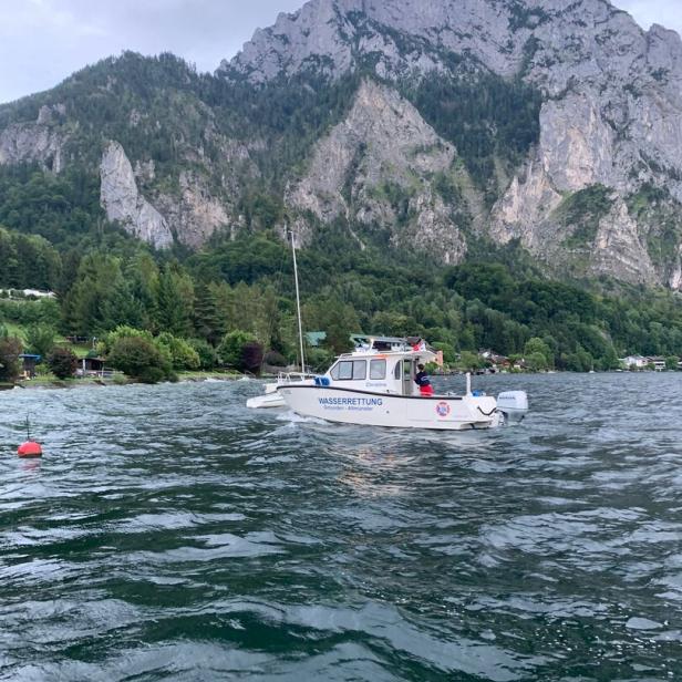 Ein Wasserrettungsboot fährt auf einem See vor einer Bergkulisse.