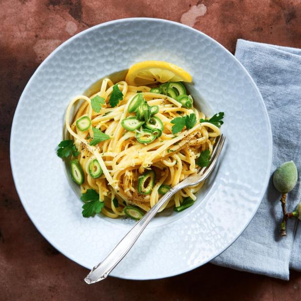 Ein Teller Linguine mit grünen Mandeln, Zitrone und Petersilie auf einem Tisch.