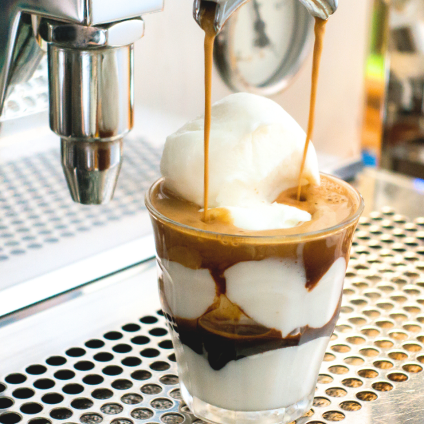 Ein Affogato wird zubereitet, wobei Espresso über eine Kugel Eis gegossen wird.