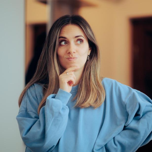 Eine Frau in einem blauen Pullover wirkt nachdenklich.