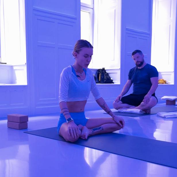 Eine Frau und ein Mann praktizieren Yoga in einem hellen Raum.