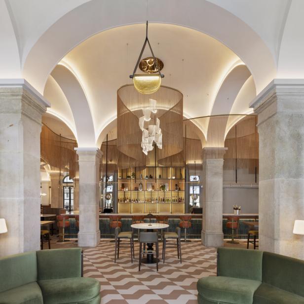 Ein elegantes Bar-Interieur mit hohen Decken, Säulen und einer auffälligen Beleuchtung über der Bar.