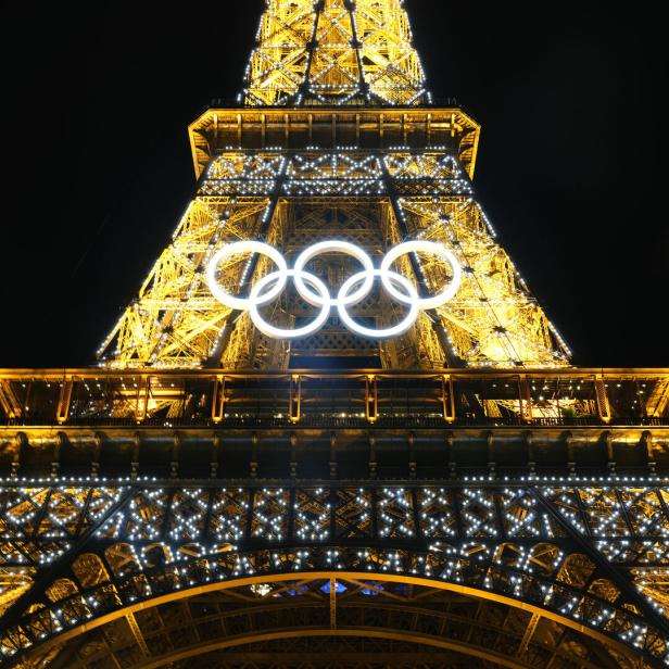 Der Eiffelturm in Paris ist nachts mit den Olympischen Ringen beleuchtet.
