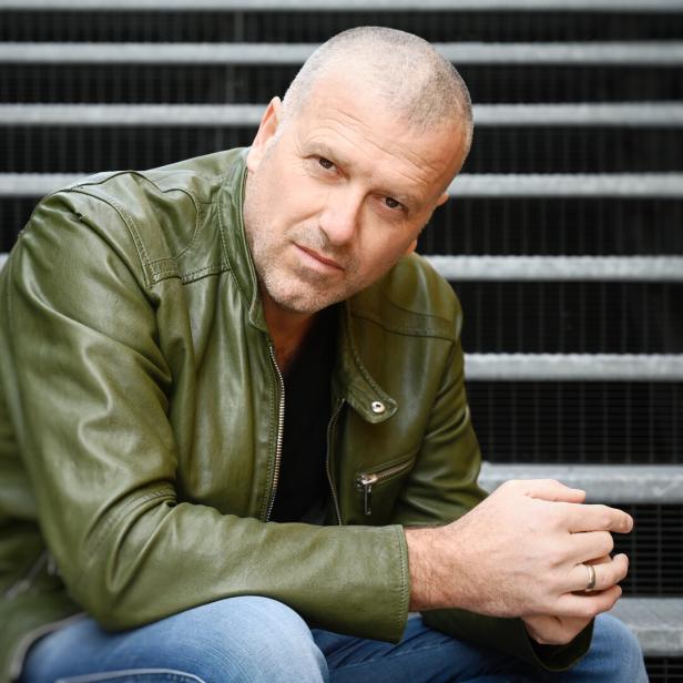 Ein Mann mit Lederjacke sitzt auf einer Treppe.