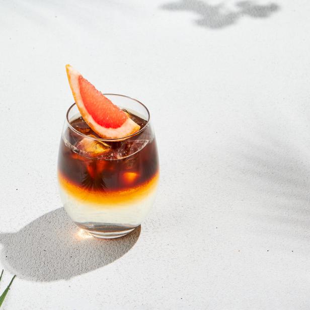 Espresso Tonic mit Orangenscheibe auf weißem Hintergrund.