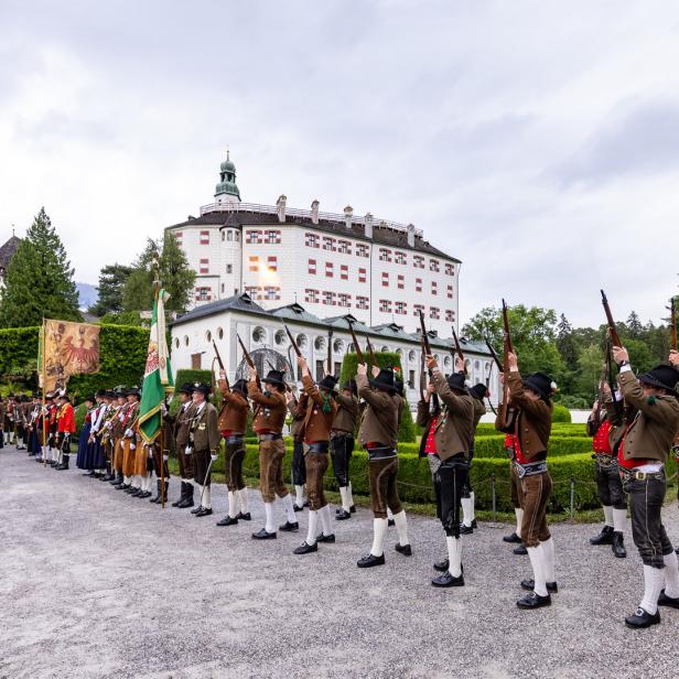 Vor Schloss Ambras feuern Schützen in Tracht mit Gewehren in die Luft.