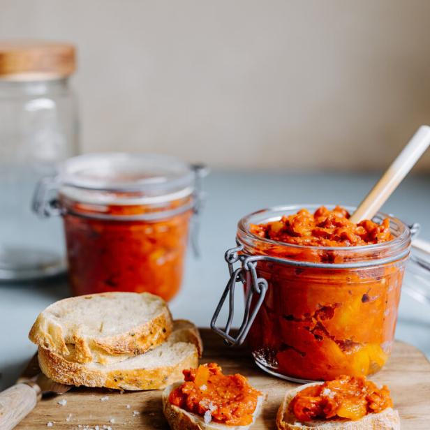 Eingemachte Paprika und Brotscheiben auf einem Holzbrett.