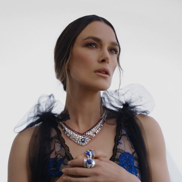 Keira Knightley trägt ein blaues Kleid und auffälligen Schmuck.