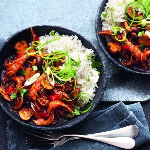 Zwei Schalen mit Reis, Schweinefleisch, Pilzen und süßer Chili-Soße, garniert mit Frühlingszwiebeln.