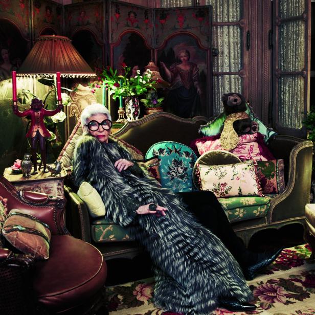 Iris Apfel ruht in einem opulenten Interieur auf einem Sofa.