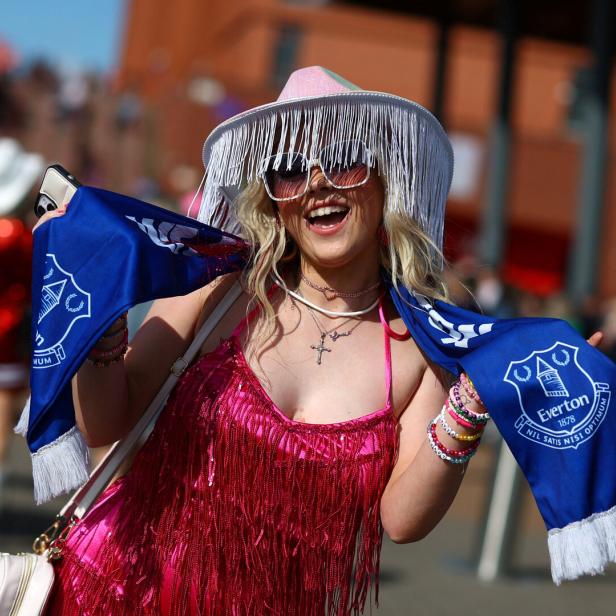 Eine lachende Frau mit einem Schal des FC Everton und einem pinkfarbenen Paillettenkleid.