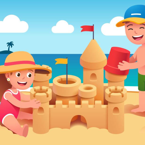 Zwei Kinder bauen eine Sandburg am Strand.