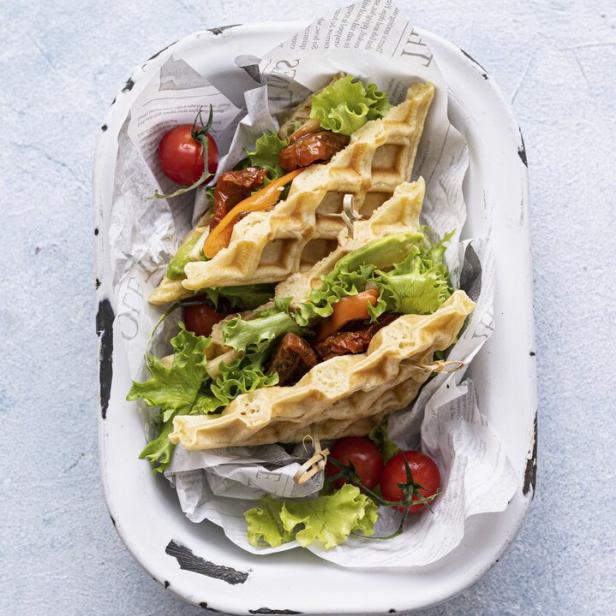 Herzhafte Waffeln mit Salat, getrockneten Tomaten und Karotten in einer Schale.