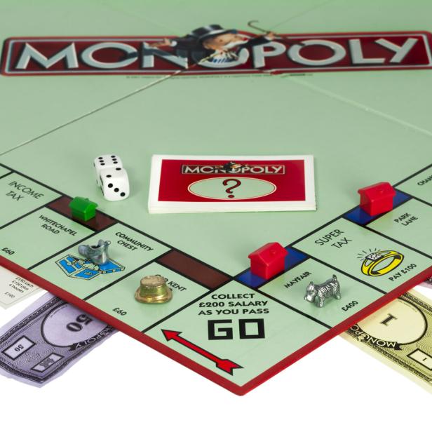 Ein Monopoly-Spielbrett mit Spielfiguren, Häusern und Spielkarten.
