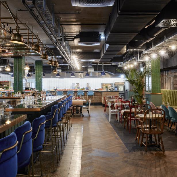 Innenansicht des Restaurants Seven North mit Bar, Tischen und offener Küche.