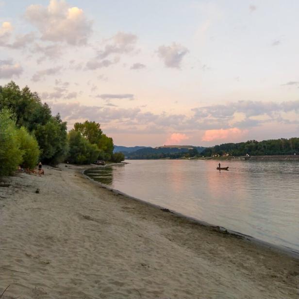 Ein Sandstrand in Luberegg mit einem kleinen Boot auf dem Fluss.