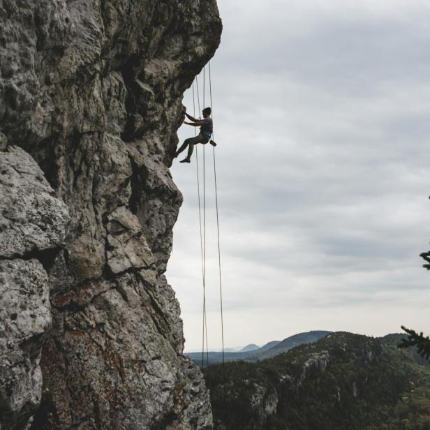 Ein Mann klettert an einer Felswand in den Alpen.