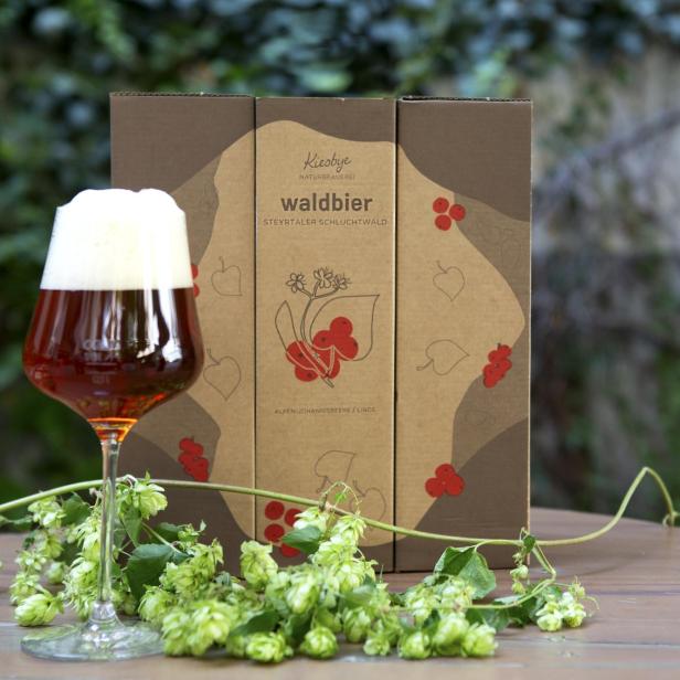 Ein Glas Waldbier der Naturbrauerei Kiesbye vor einer passenden Geschenkverpackung.