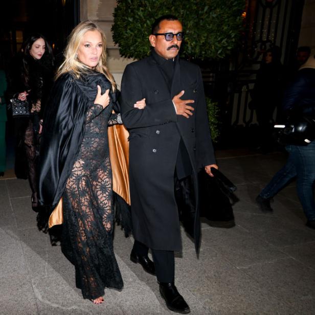 Kate Moss wird von einem Mann gestützt, während sie ein Gebäude verlässt.