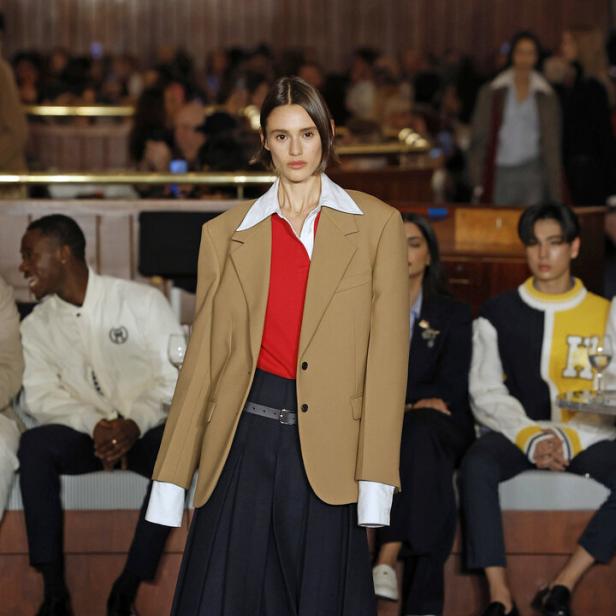 Eine Frau präsentiert einen beigen Blazer und einen Faltenrock von Tommy Hilfiger.