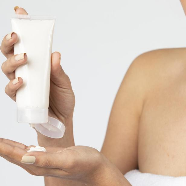 Frau versucht Bodylotion aus einer Tube zu drücken.