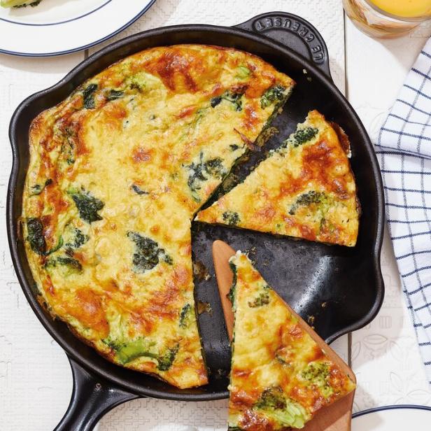 Eine Gemüse-Frittata in einer gusseisernen Pfanne, ein Stück wird herausgenommen.