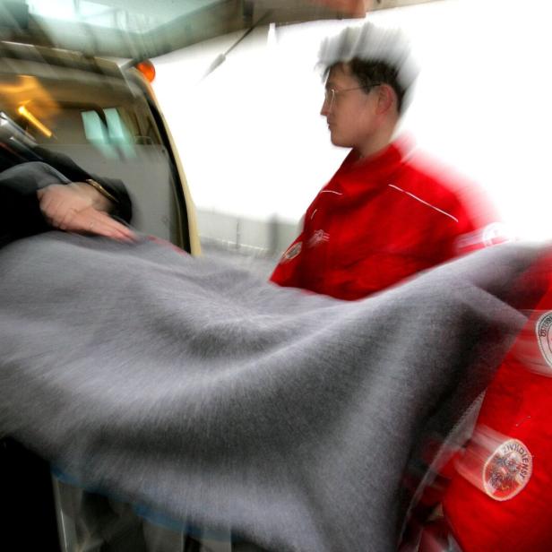 Rettungssanitäter schieben eine Patientin auf einer Trage in einen Krankenwagen.