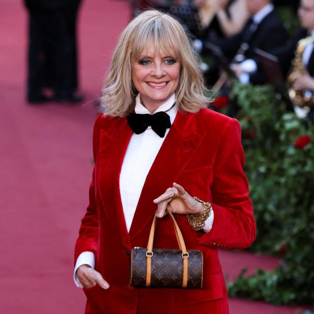 Twiggy in einem roten Samtanzug mit einer Louis Vuitton Handtasche.
