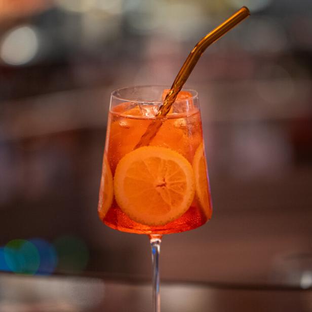 Ein Pampelle Royal Cocktail mit Orangenscheiben und einem Strohhalm.