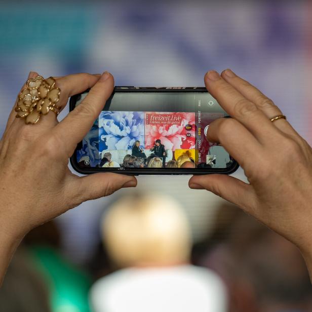 Eine Person fotografiert mit einem Smartphone eine Veranstaltung von „freizeit.live“.