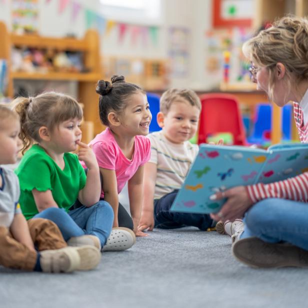 Eine Kindergartenpädagogin liest Kindern ein Buch vor.