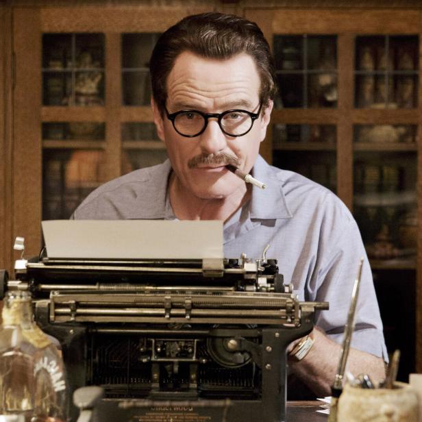 Bryan Cranston als Dalton Trumbo mit Zigarette und Schreibmaschine.