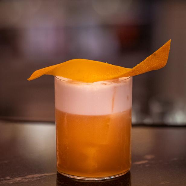 Ein Whiskey-Cocktail, ein Autumn Sour, mit Orangenzeste garniert.