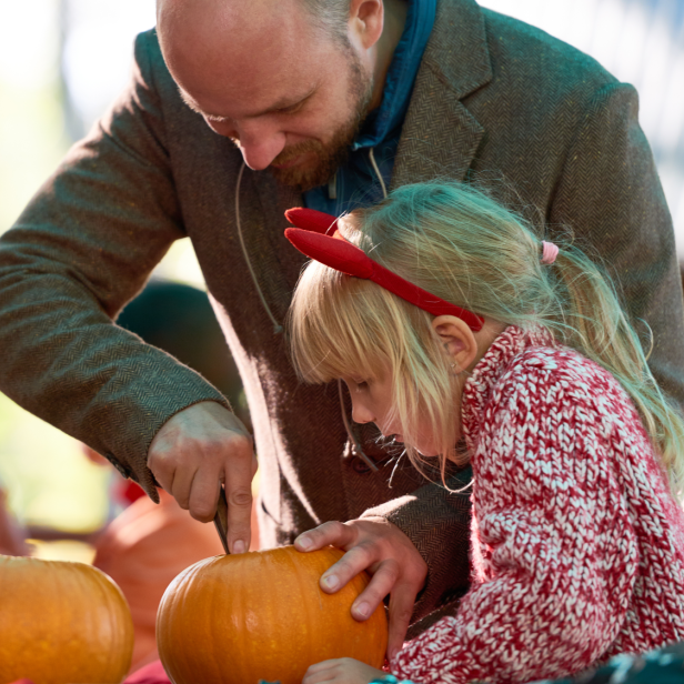 Vater und Tochter schnitzen gemeinsam einen Kürbis für Halloween.
