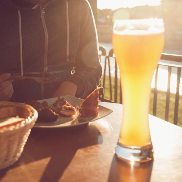 Eine Person isst im Biergarten bei Sonnenuntergang.