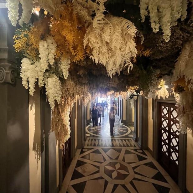 Ein mit Blumen geschmückter Gang mit Menschen im Hintergrund.