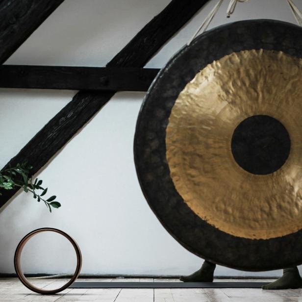 Ein Gong steht in einem Raum mit Holzbalken und einer Zimmerpflanze.