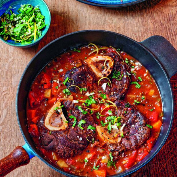 Wild-Ossobuco in einer Pfanne mit Gemüse und Kräutern.