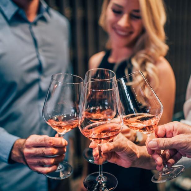Vier Personen stoßen mit Rosé-Schaumwein an.
