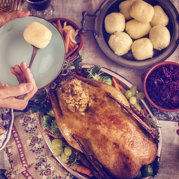 Ein festlicher Tisch mit Gans, Knödeln und Rotkohl wird angerichtet.