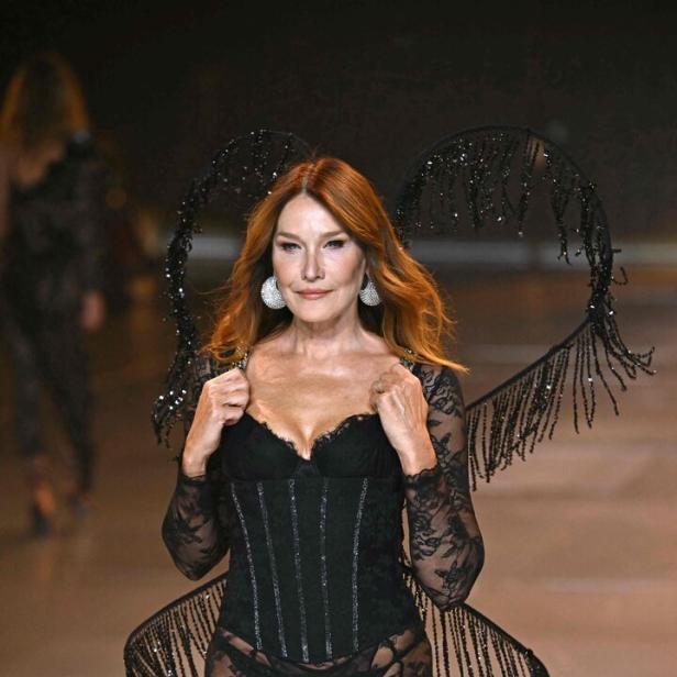 Carla Bruni läuft in schwarzer Spitze und herzförmigen Flügeln über einen Laufsteg.