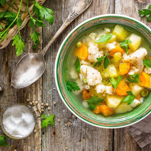 Eine Schüssel Gemüsesuppe mit Karotten, Blumenkohl und Petersilie.