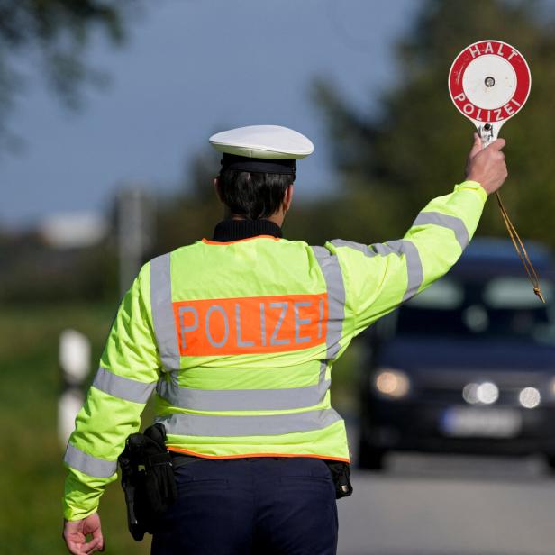 Eine uniformierte Person in Signalfarben, die am Straßenrand Autos anhält.