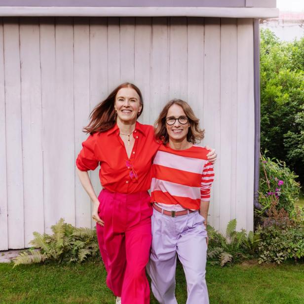 Zwei Frauen in farbenfroher Kleidung stehen im Garten nebeneinander.